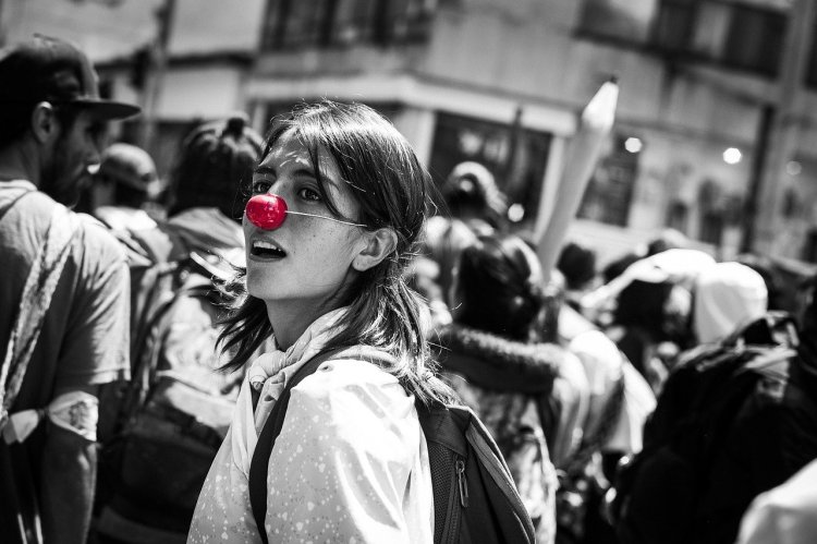 A Black and White Picture with a woman wearing a red clown nose